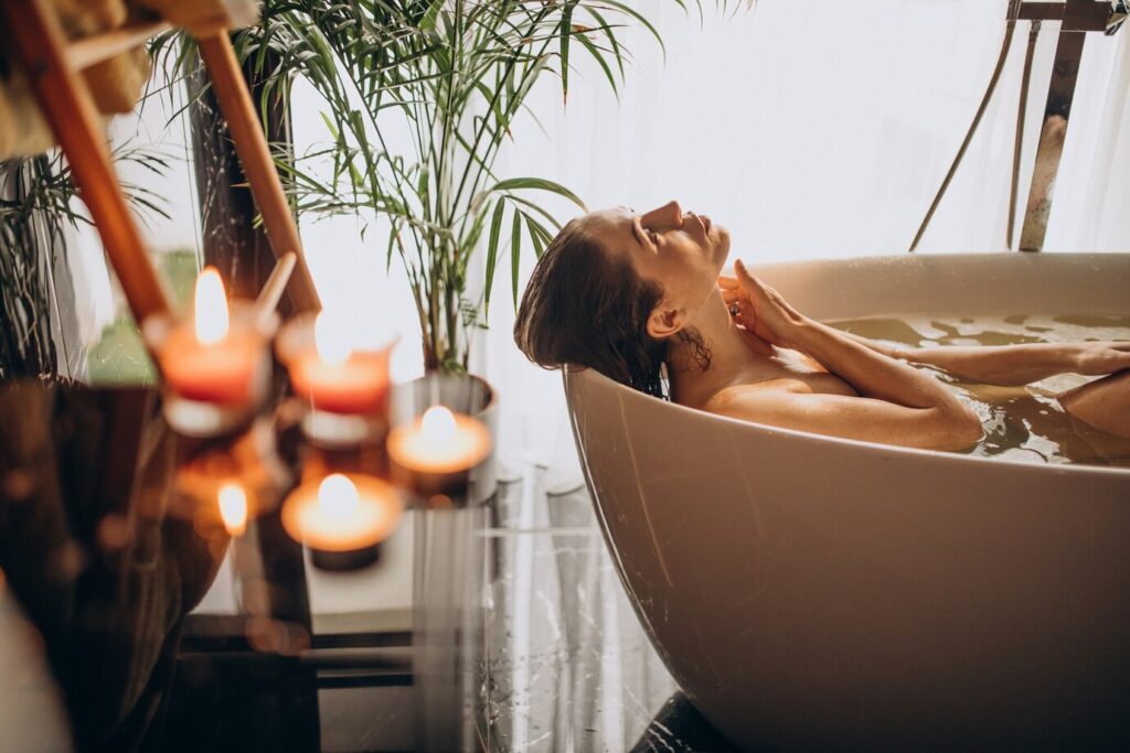 Na imagem, uma mulher tomando banho terapêutico e refletindo.