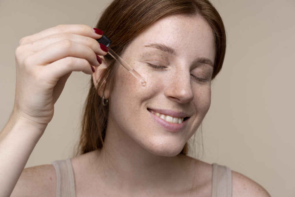 Uma mulher aplicando um sérum de ácido málico em seus rosto.